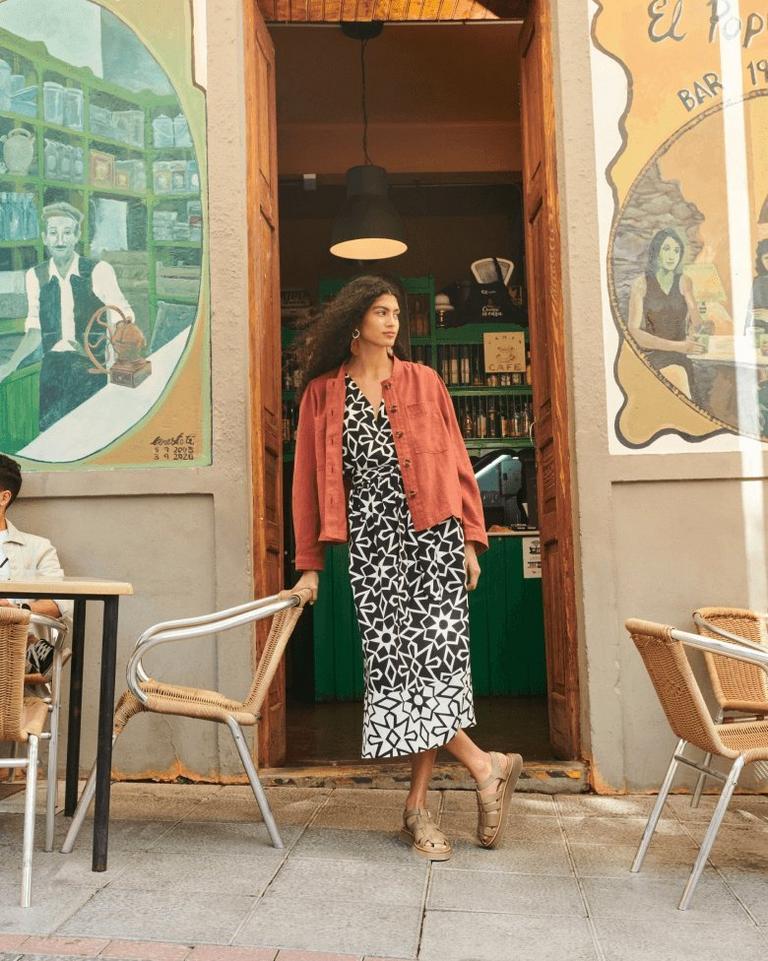 Woman leaning in doorway wearing linen dress and linen jacket